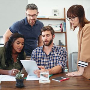 Two men and two women in an office looking at a tablet device