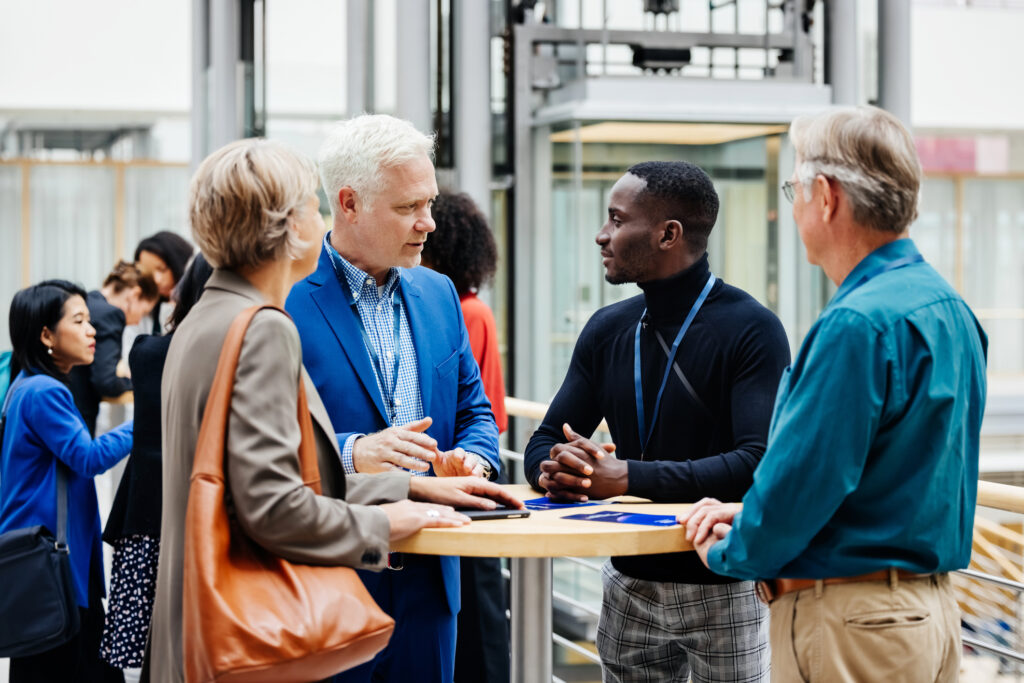 A group of business conference participants discussing a presentation in the hotel foyer together.